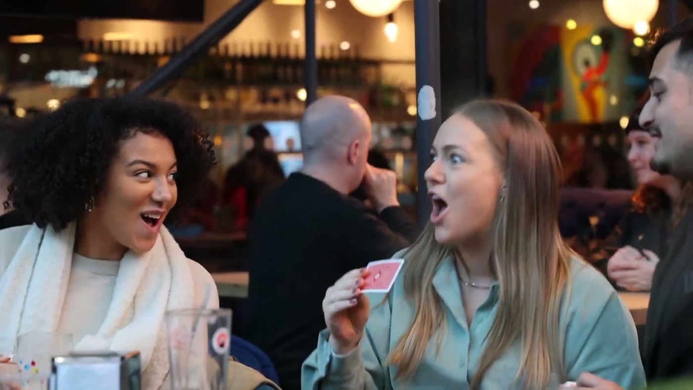 Two guests reacting in astonishment to a card trick