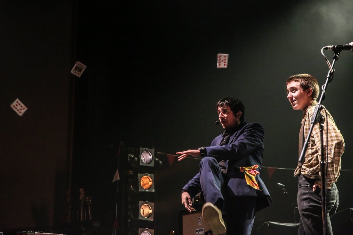Ben Sharp on stage throwing a fan of playing cards into the air during a live show