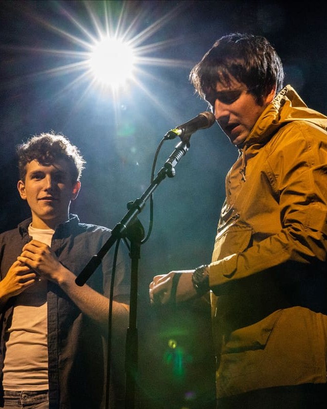 Ben Sharp performing a magic routine on stage with a volunteer from the audience