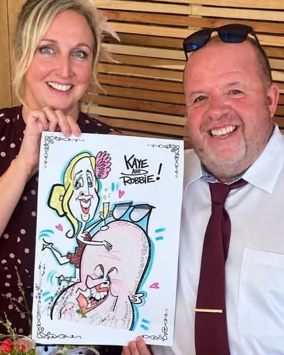 Couple at a wedding holding their colour caricature