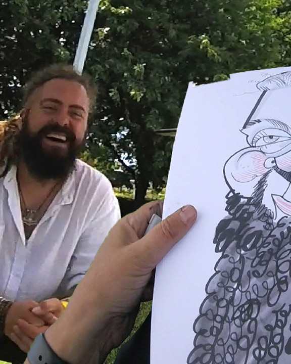 Bearded guest watching his caricature being drawn outdoors
