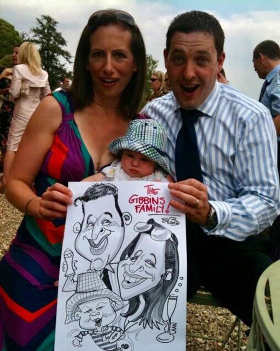 Family with their baby holding a family caricature