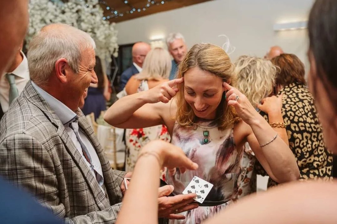 A guest covering her ears in disbelief as playing cards are spread in front of her