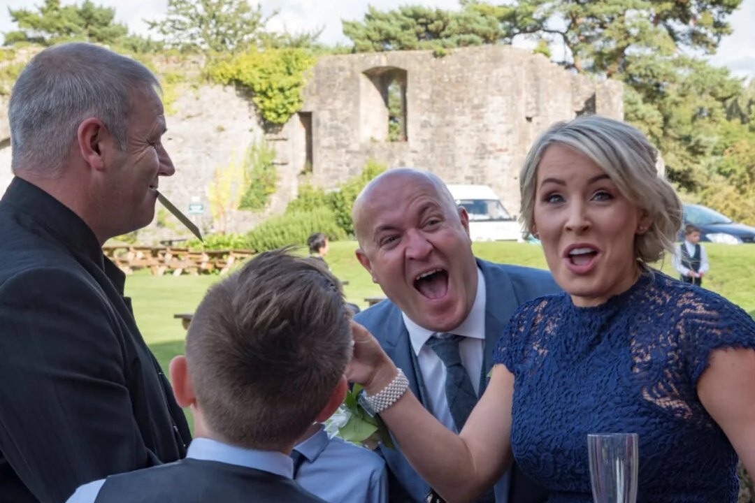 Wedding guests roaring with laughter at a close-up routine in the grounds of a castle