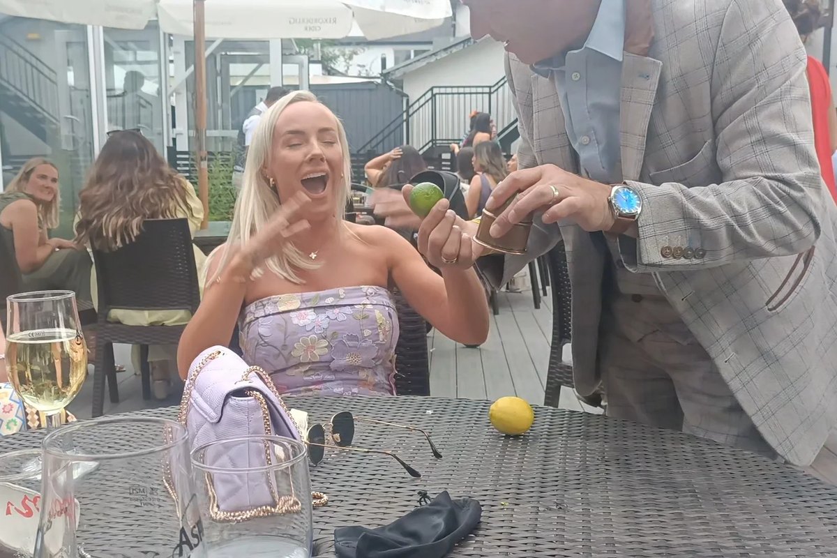 A guest laughing as the magician makes a lime appear on the table in front of her