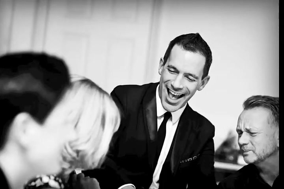 The magician laughing with guests after a card trick at a dinner party
