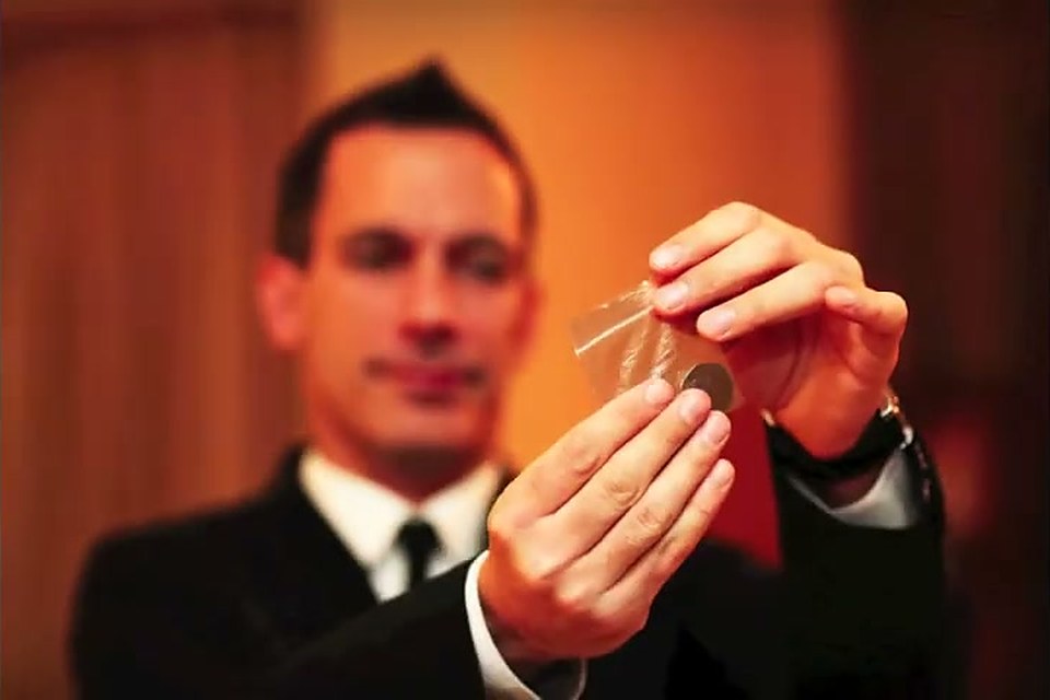 The magician holding up a playing card during a close-up routine