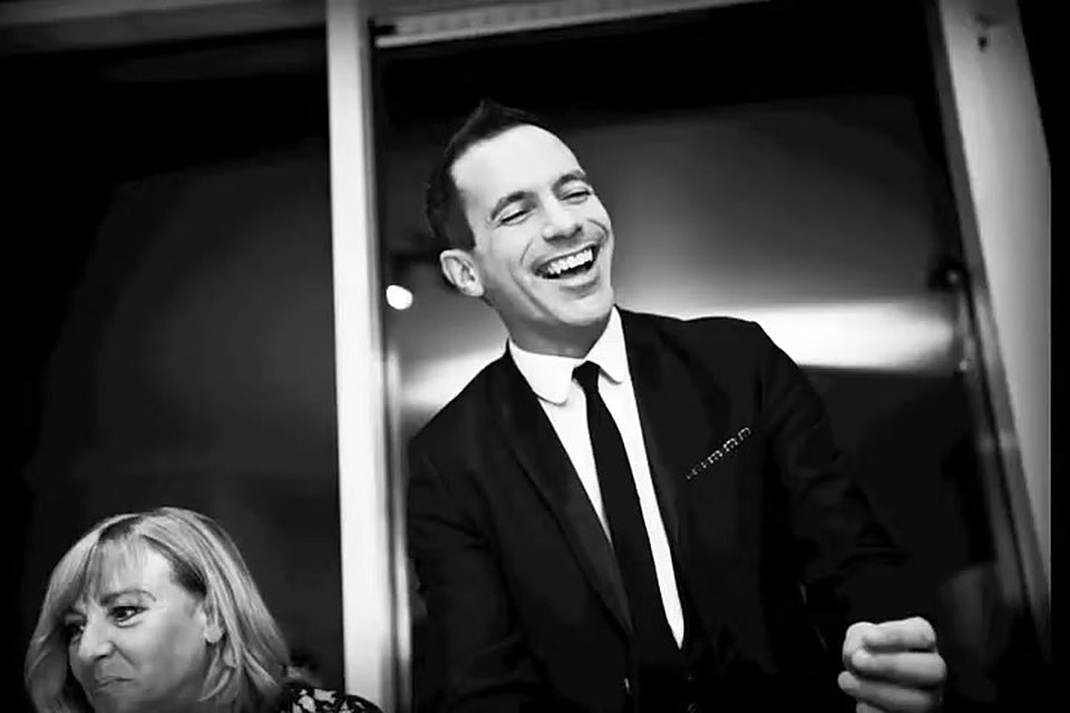 The magician laughing with a seated guest at a private party