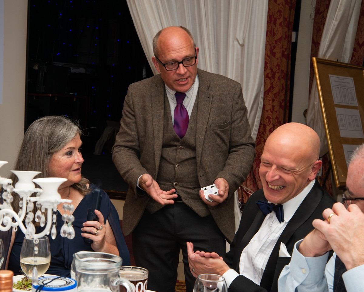Guests laughing at a dinner table as the magician performs close-up magic