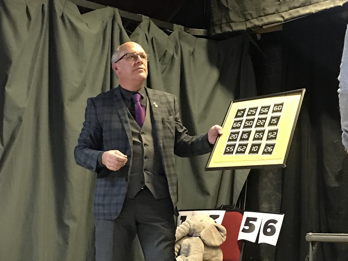 The magician on stage with a number board during a mind reading routine