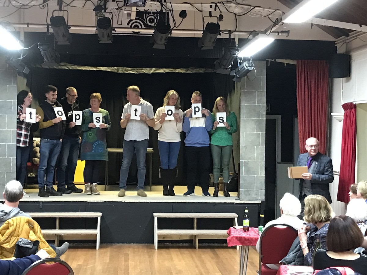 Audience volunteers on stage holding up letter cards during the stand-up show