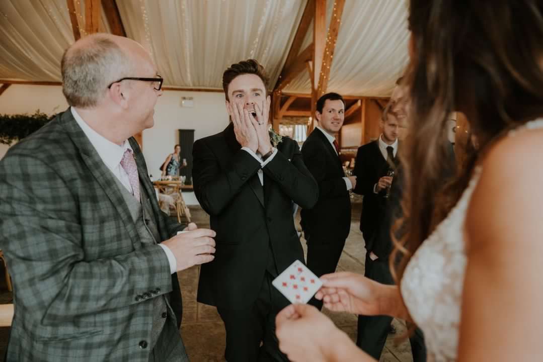 Wedding guests reacting with shock to a card trick from the magician