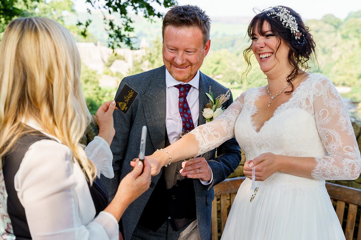 Aurora Myst performing close-up magic for a bride and groom outdoors