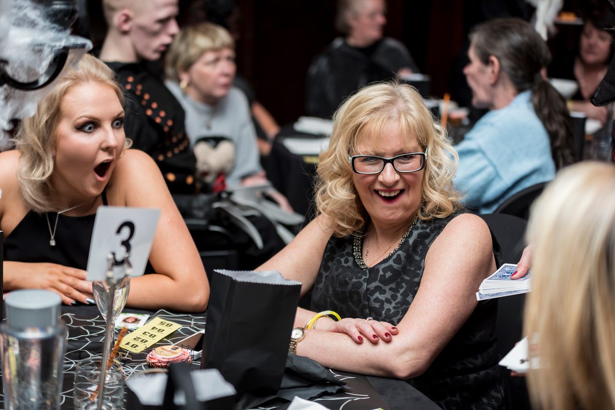 Guests at a gala dinner table open-mouthed after a magic trick
