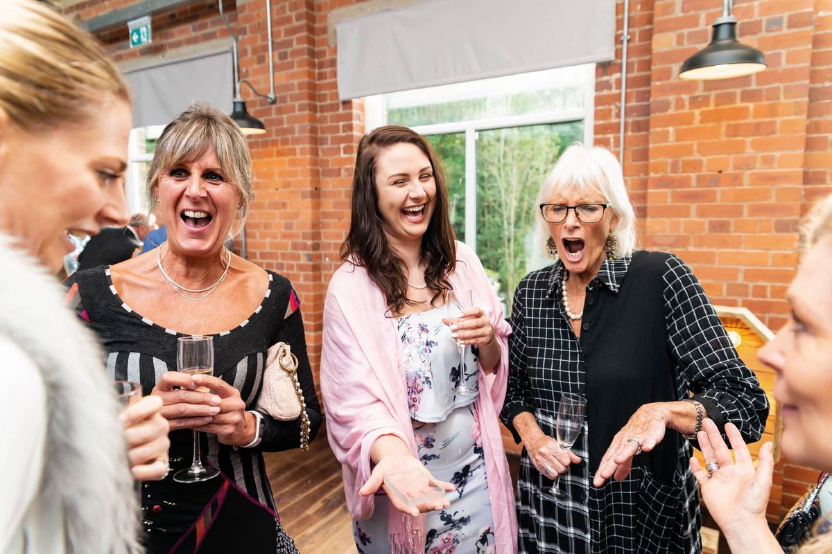 Women at a party gasping and laughing at a card trick