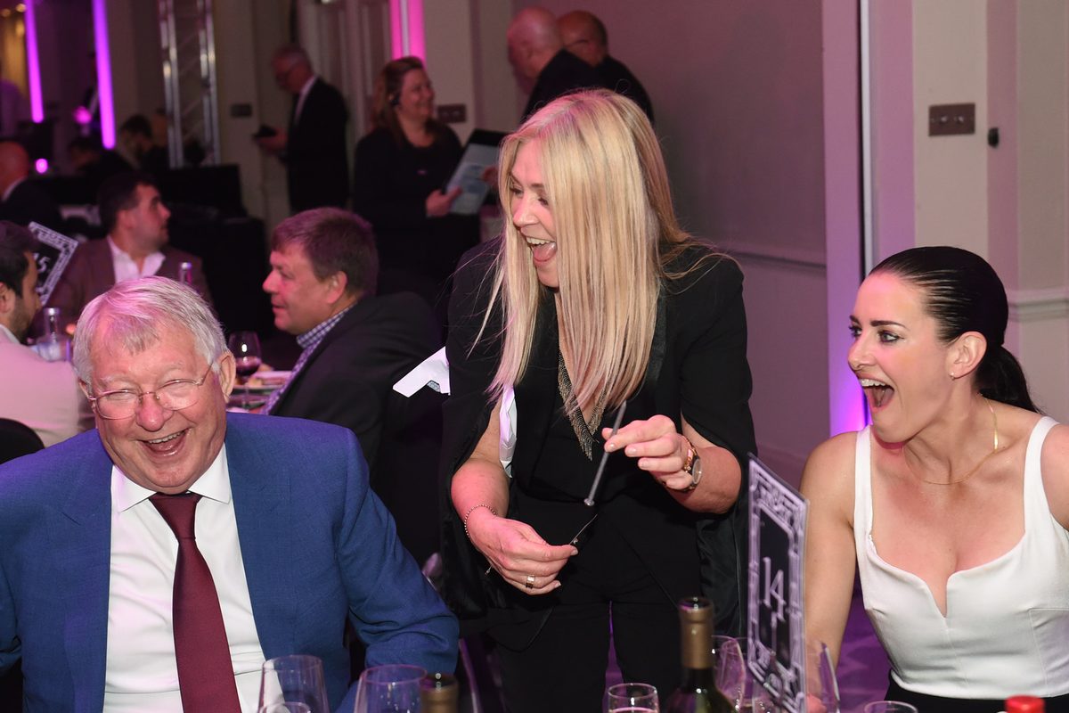 Aurora Myst performing magic at a dinner table for Sir Alex Ferguson