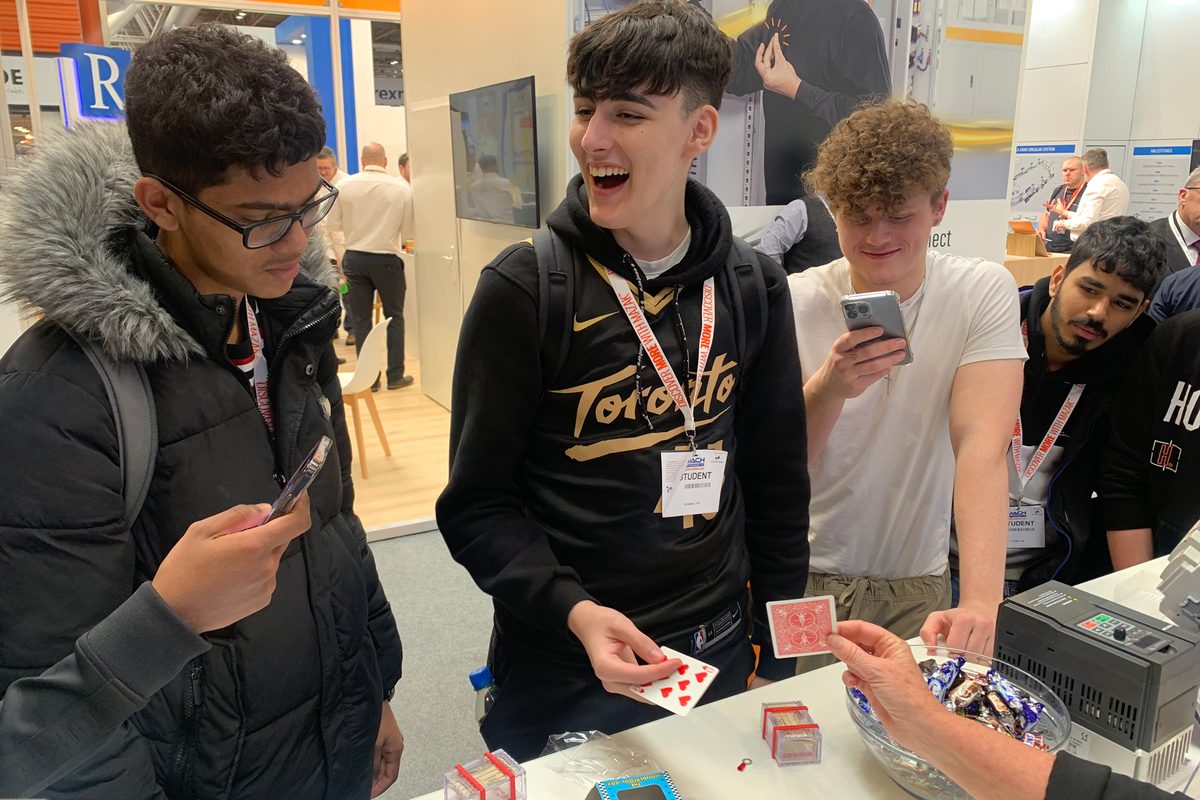 Young trade show visitors reacting to card magic at an exhibition stand