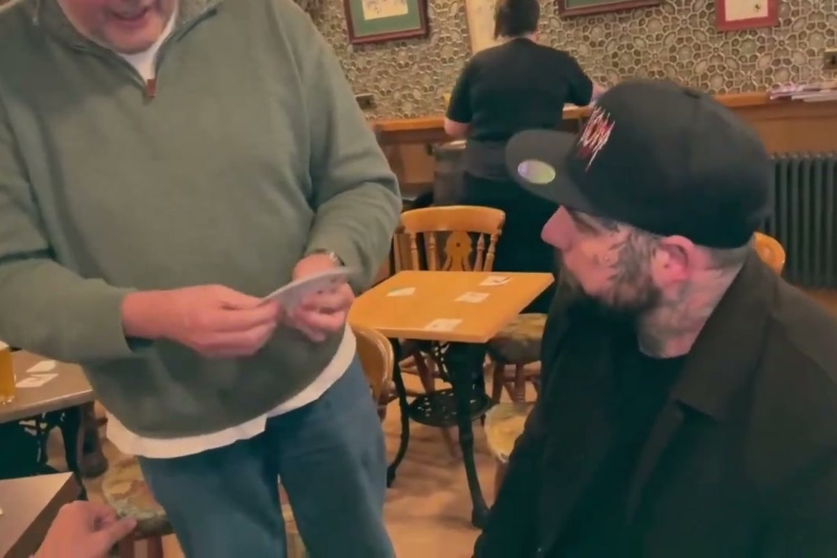 Banter Magic showing a card to a seated guest in a busy pub