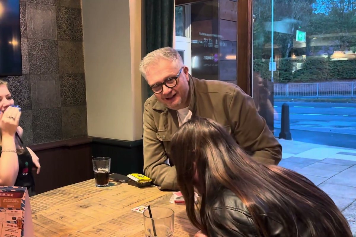 A guest laughing with her hand over her mouth as Banter Magic reveals a card