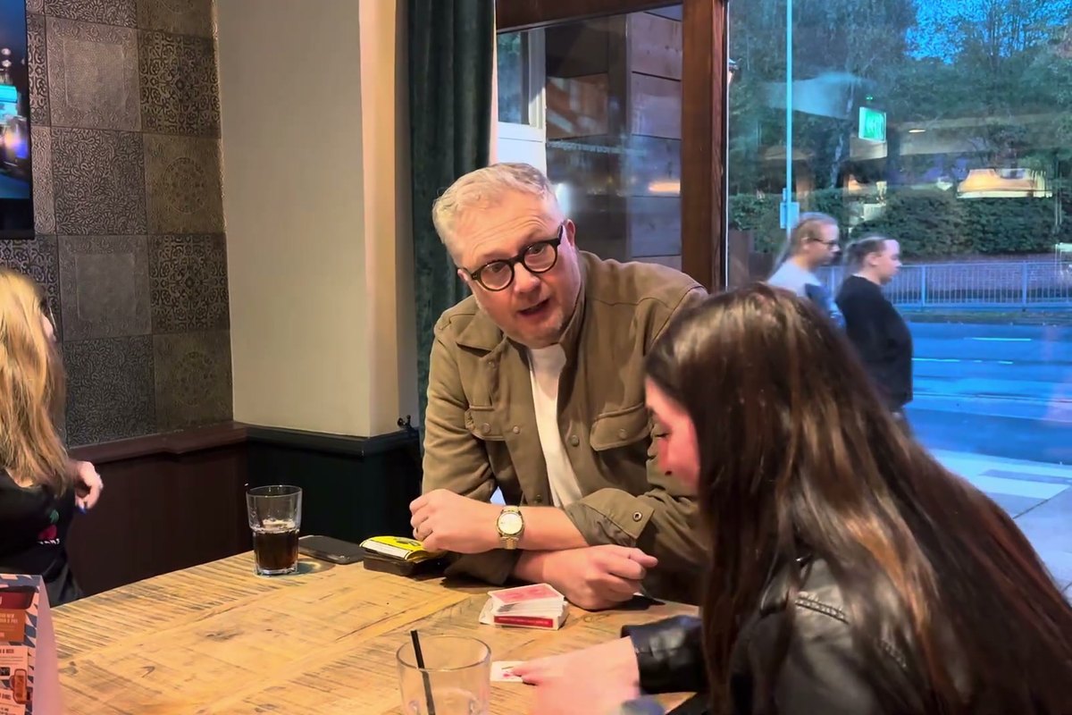 Banter Magic leaning in at the table during a close-up card routine