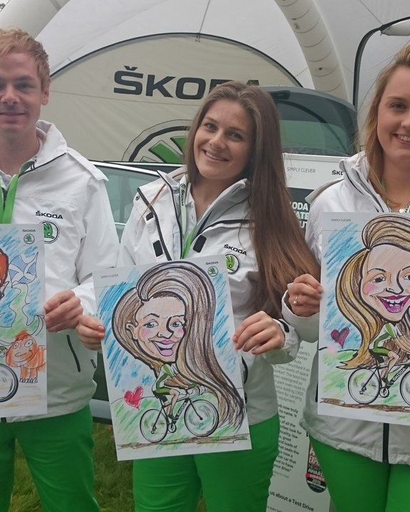 Three event staff holding their colour caricatures at a cycling race