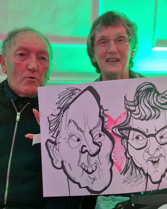 Couple holding their caricature at a party