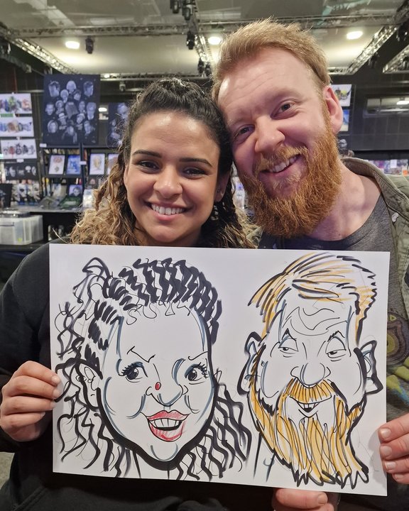 Couple holding their caricature at a public event