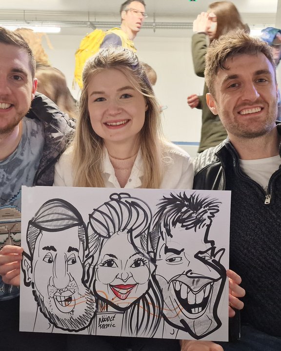 Three friends holding their group caricature at a shopping centre event