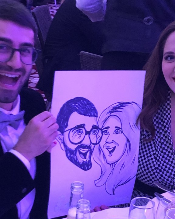Couple at a gala dinner holding their caricature