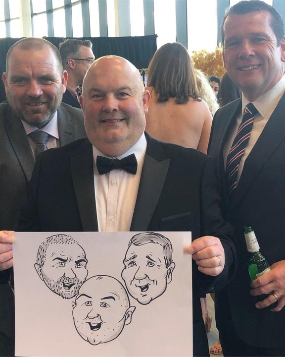 Three guests holding their group caricature at an awards dinner