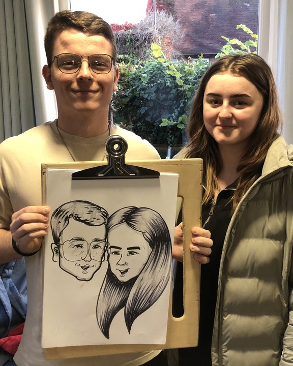 Couple holding their caricature on a clipboard at a party