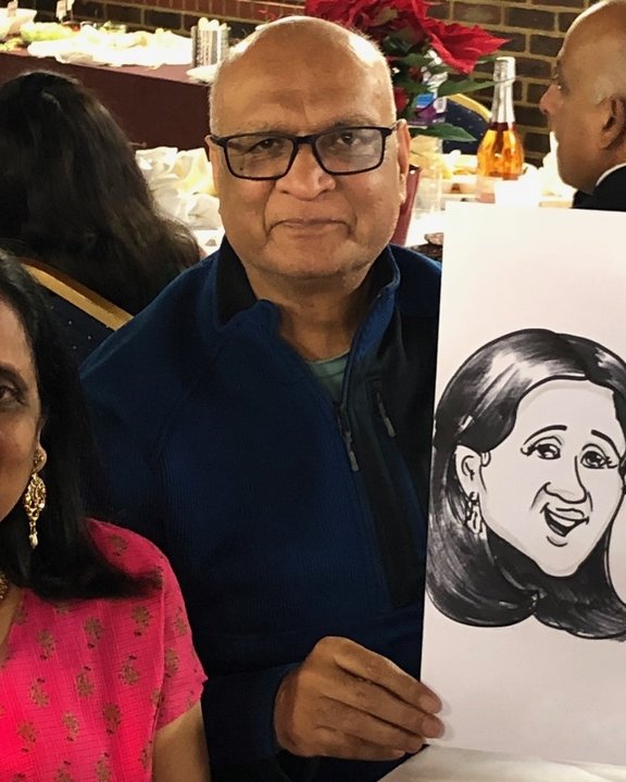 Couple holding their caricature at a family celebration