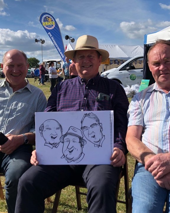 Group holding their caricature at a country show