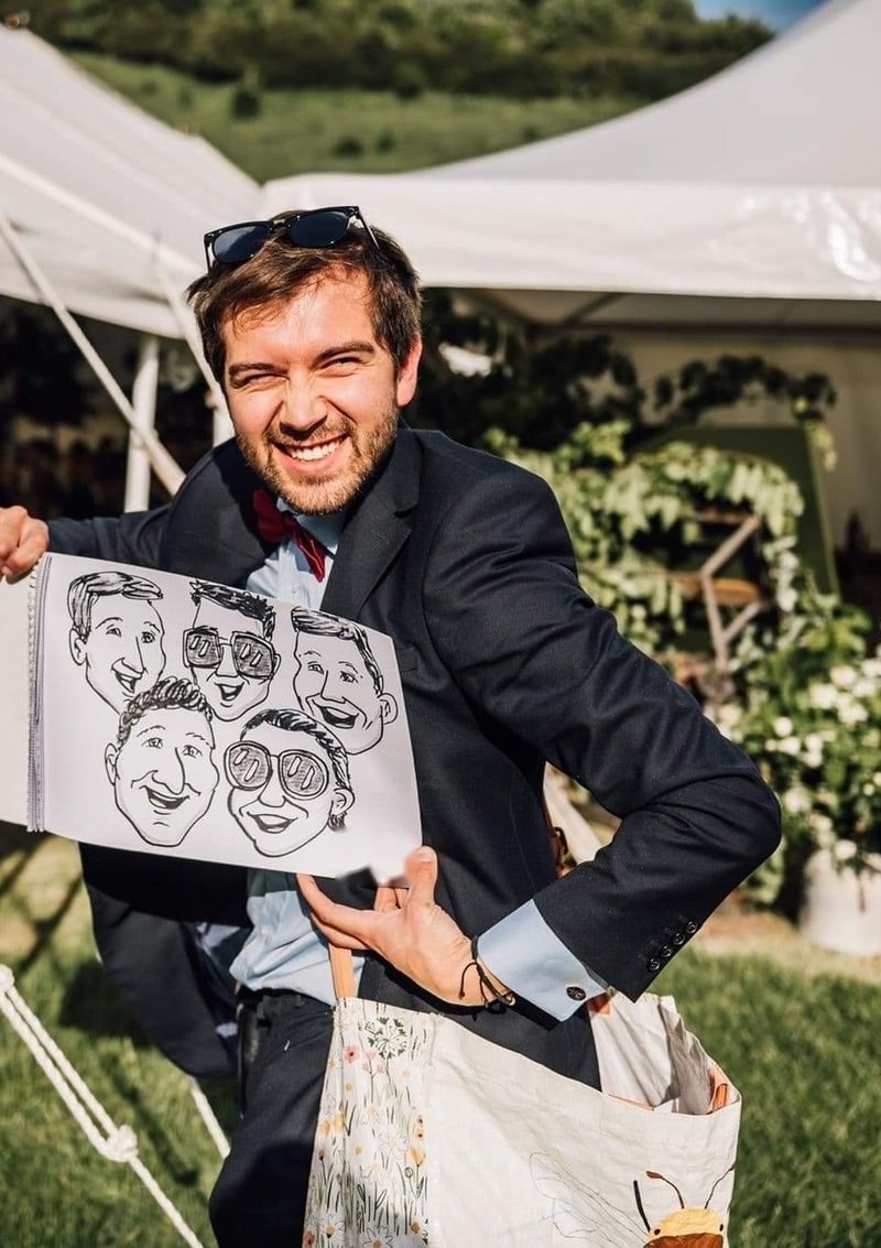 Capital Caricatures artist holding up a finished group caricature in a marquee