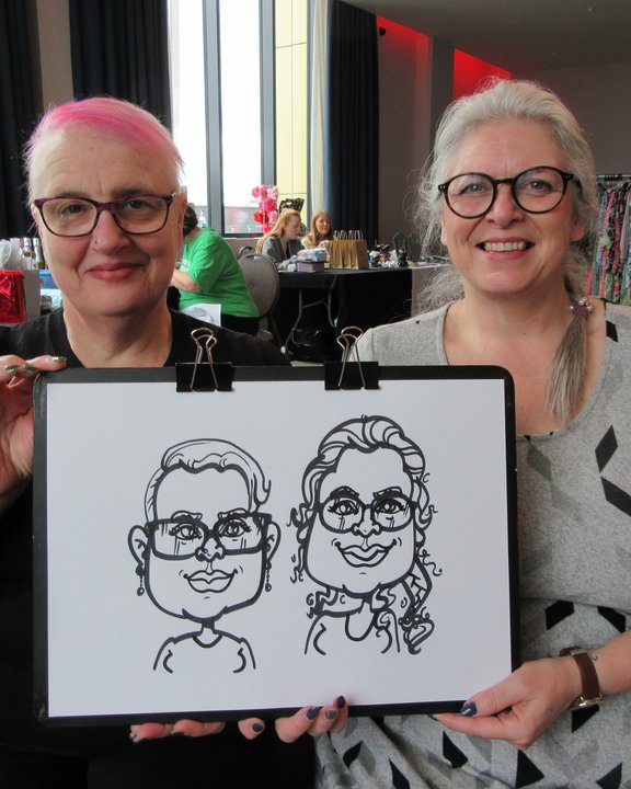 Two guests holding their shared black and white caricature at a party