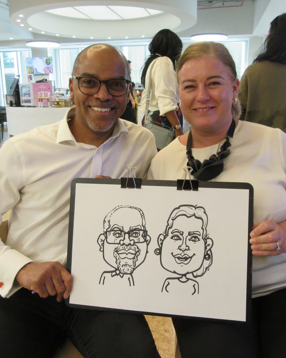 Couple holding their double caricature at a corporate event