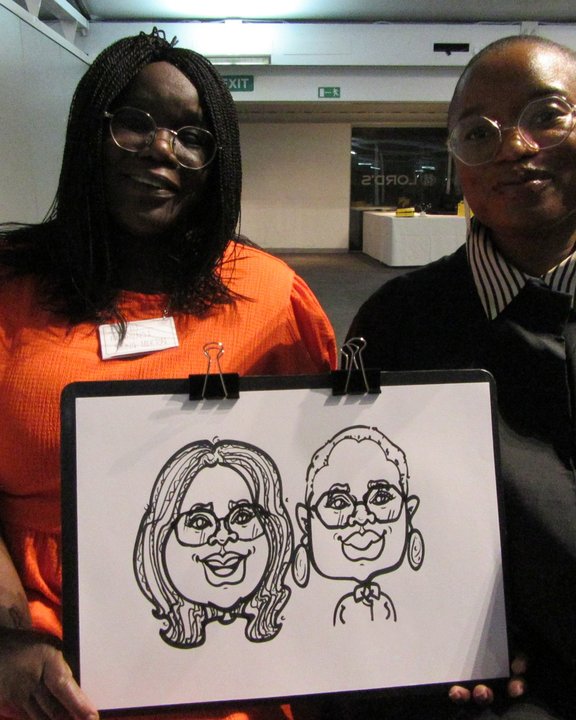 Two guests holding their double caricature at an event