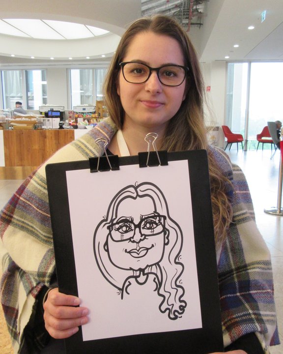 Guest in glasses holding her caricature at a corporate event