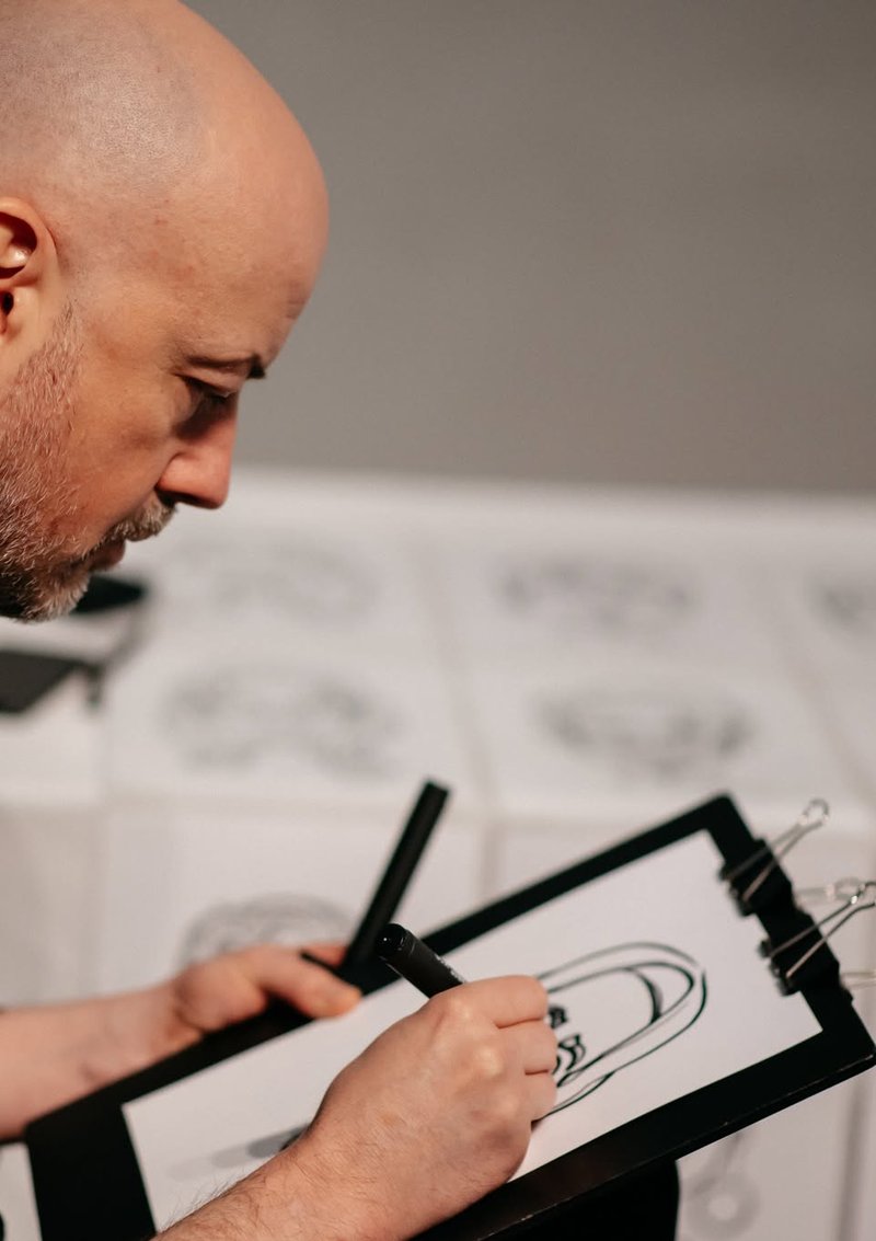 Charming Caricatures artist drawing a live caricature with a black marker at an event
