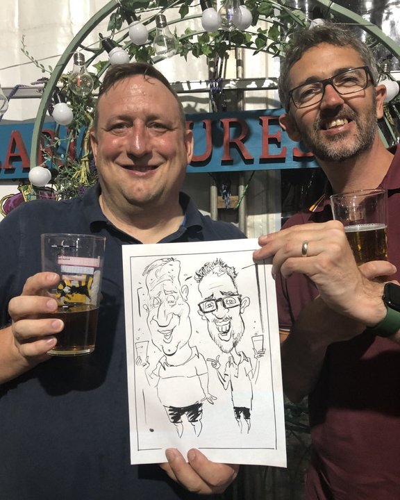 Two festival-goers holding their live caricature