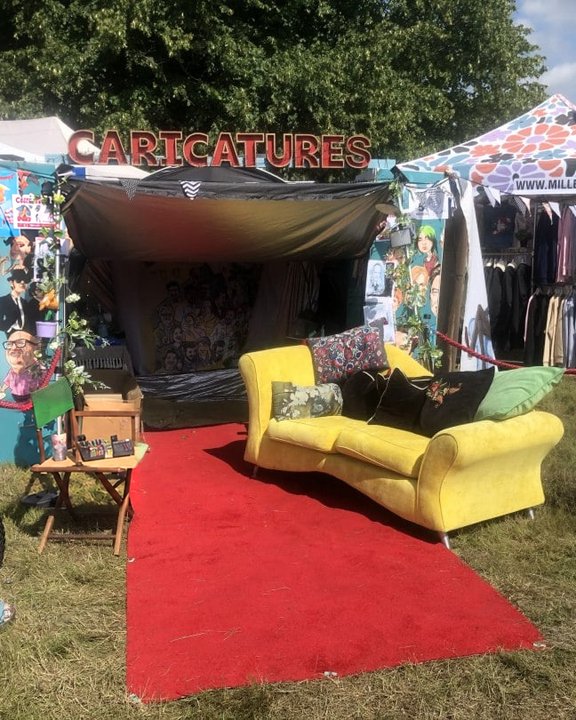 Caricature stand with a red carpet and yellow sofa at a festival