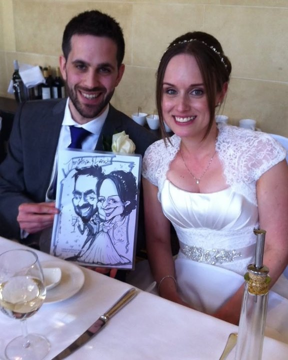 Bride and groom holding their caricature at the wedding breakfast