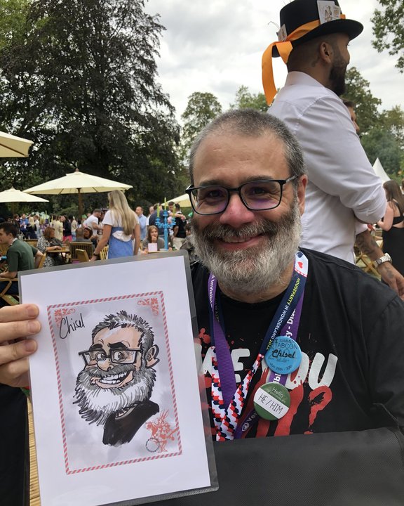 Bearded guest in glasses holding his colour caricature at a summer garden party