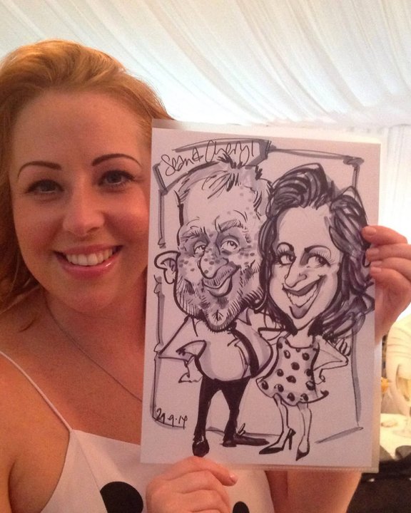 Smiling guest holding a black and white couple caricature at a wedding