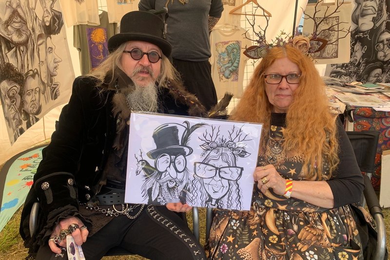 Couple in festival costume holding their caricature