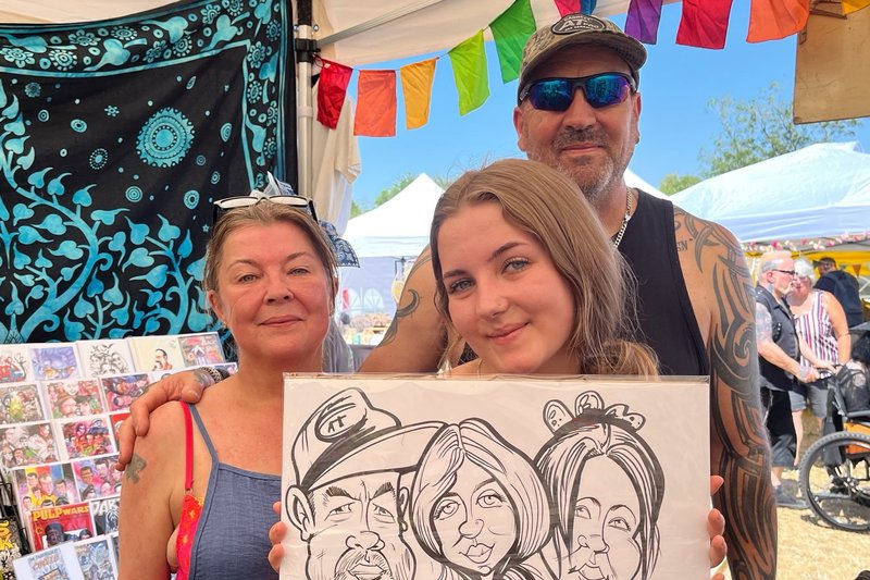 Family holding their group caricature at a summer festival