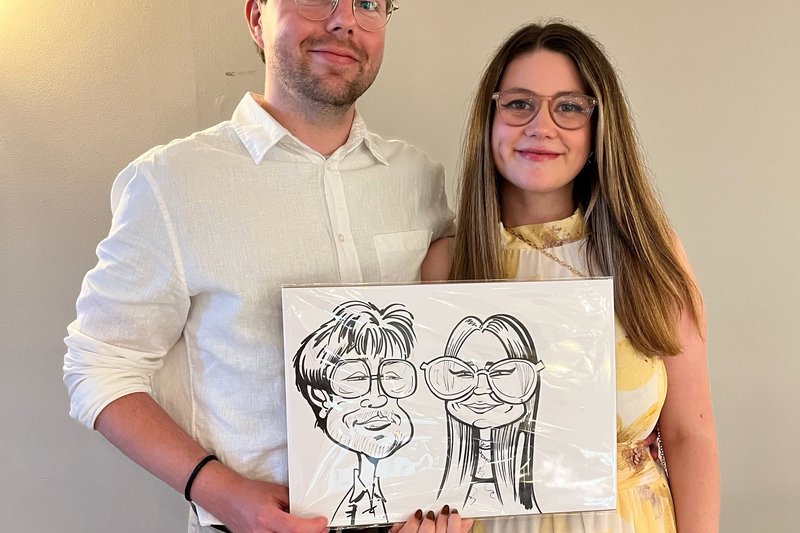 Couple holding their caricature at an evening party