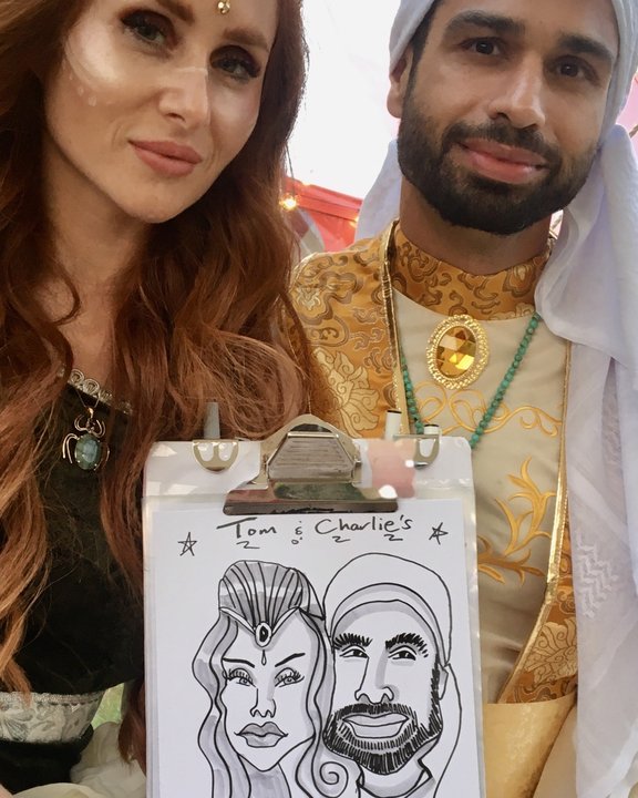 Couple in fancy dress holding their live caricature at a themed party