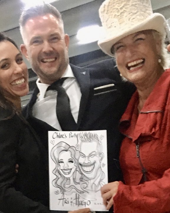 Guests holding their caricature with the artist at a party