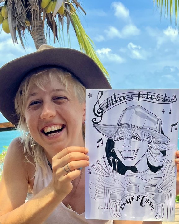 Guest holding her caricature at an outdoor event by the sea